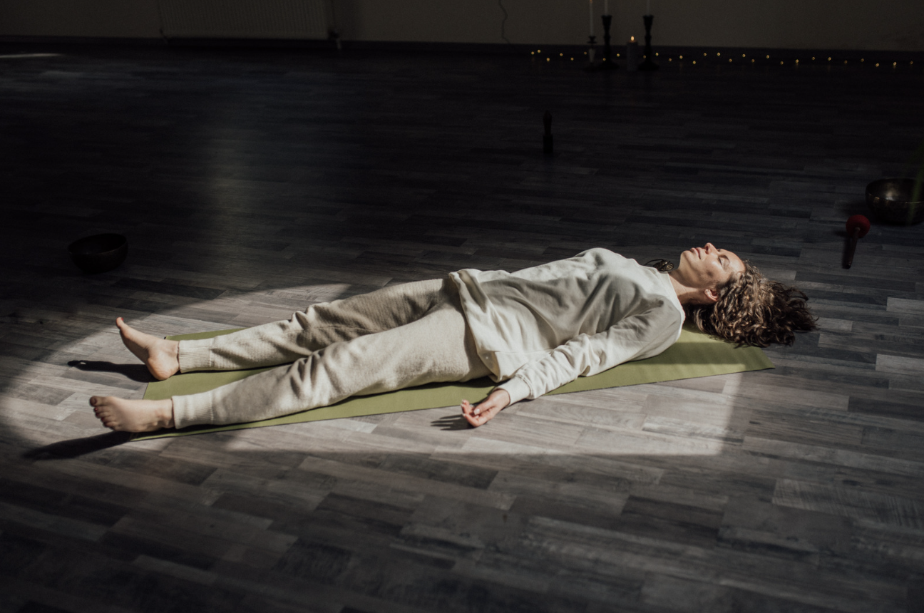 Woman lying in Shavasana during a Yoga Nidra guided meditation in Venice, FL