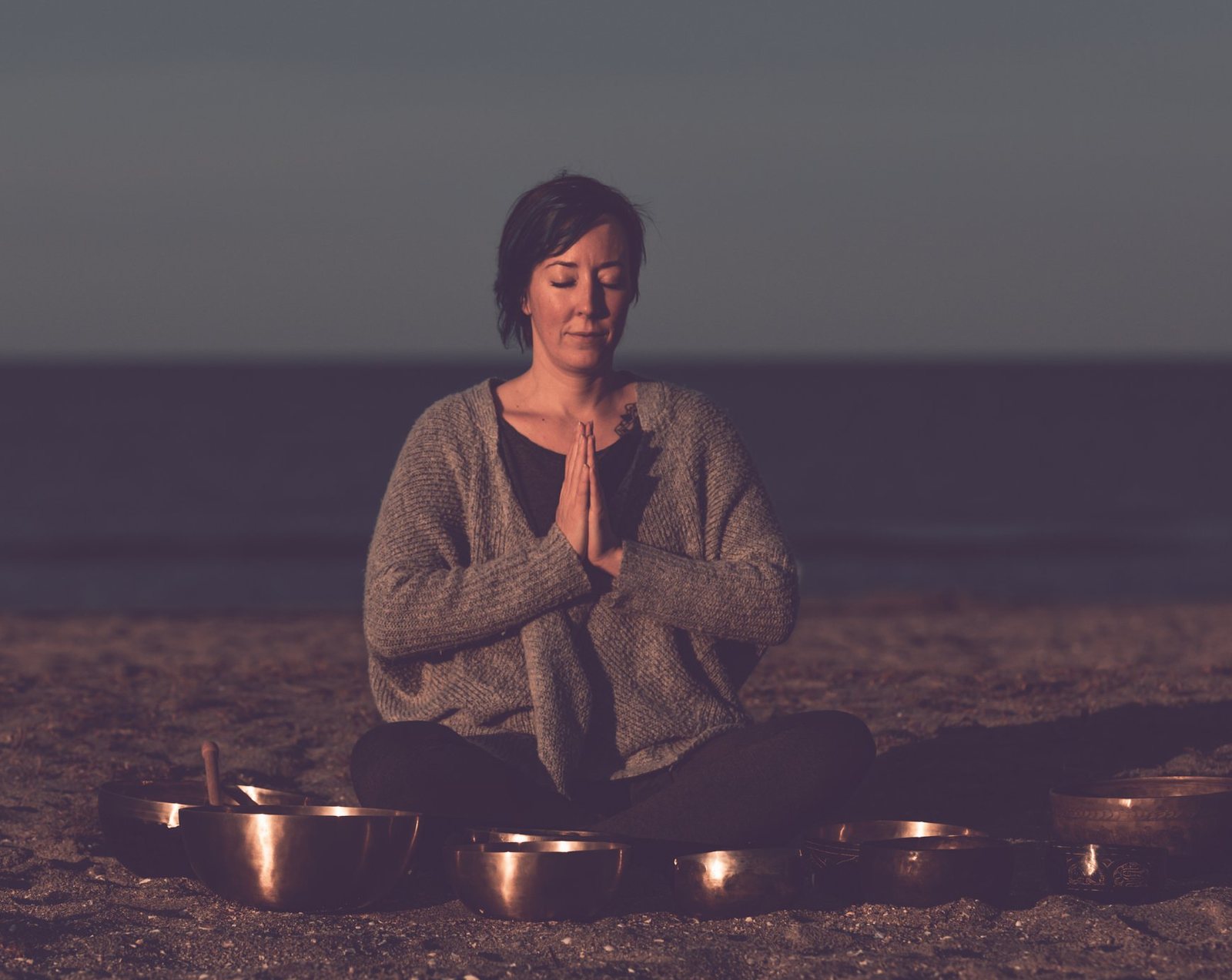 Sound healing practitioner meditating on the beach with Tibetan singing bowls, Self-Care Center, Venice, FL
